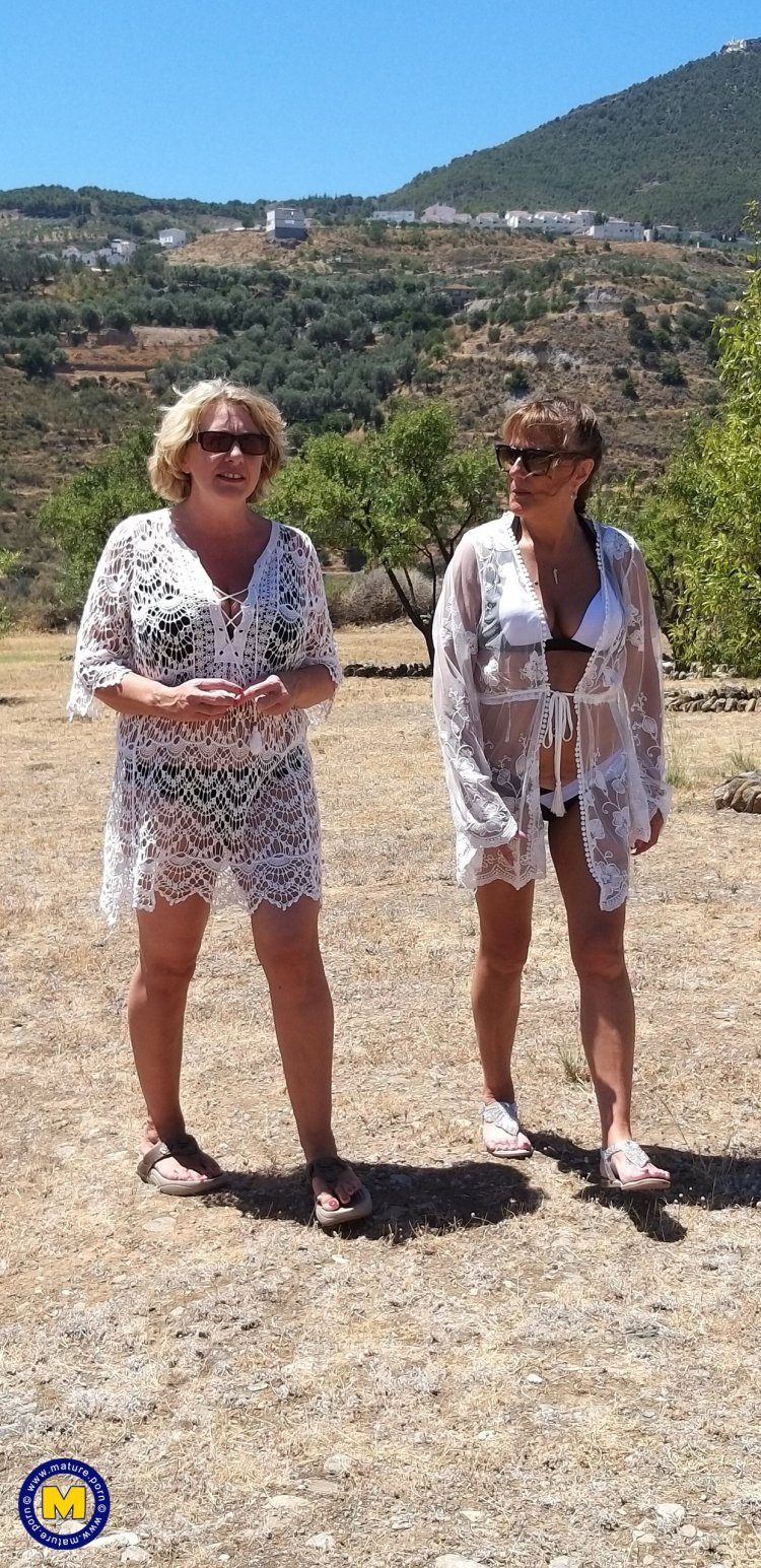 Two mature lesbians are licking in an open field in the sun
